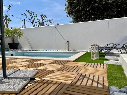 a backyard with a swimming pool and a wooden deck at Le sauvage in La Tremblade
