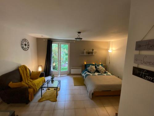 een slaapkamer met een bed en een bank bij Appartement Cosy avec jardin privatif et garage in Fontainebleau