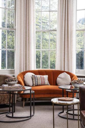 an orange couch in a living room with windows at Lincombe Hall Hotel & Spa - Just for Adults in Torquay