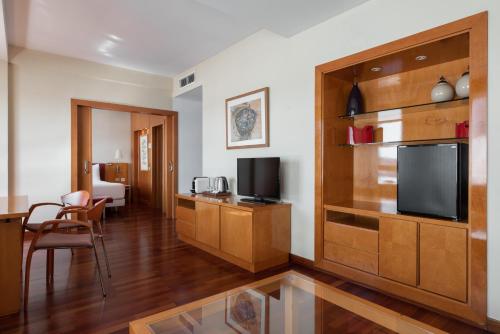 a living room with a television and a room with a table at Eurostars Atlántico in A Coruña
