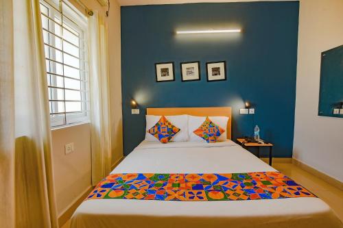 een slaapkamer met een bed met een blauwe muur bij FabHotel Sasti Inn in Chennai