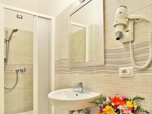 baño con lavabo, espejo y flores en Albergo Enrica, en Roma