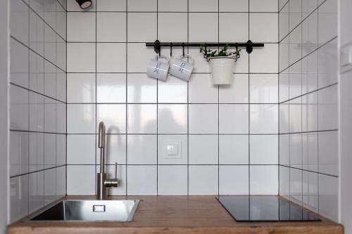 ein weiß gefliestes Bad mit einem Waschbecken und Tassen in der Unterkunft Łydynia in Ciechanów