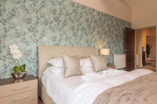 um quarto com uma grande cama branca e papel de parede floral em Heritage Serviced Suites - Serviced Apartments em Huddersfield