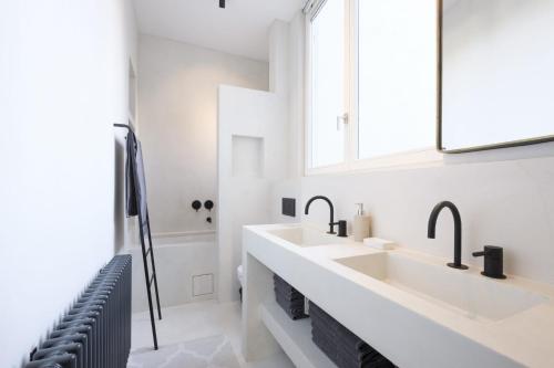 - une salle de bains blanche avec deux lavabos et un miroir dans l'établissement Cosy and Modern 2 bedrooms flat near Châtelain and Brugmann, à Bruxelles