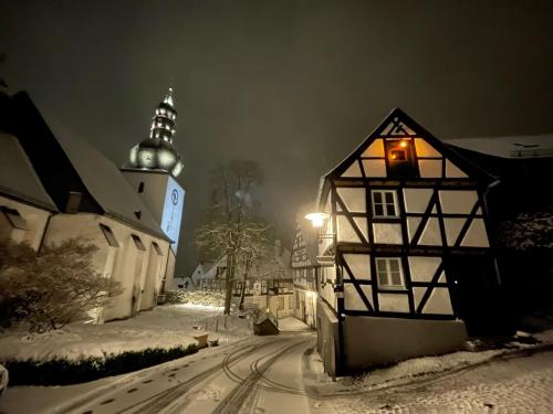 a small house in the snow with a clock tower at Kleines Bürgerhaus in Arnsberg