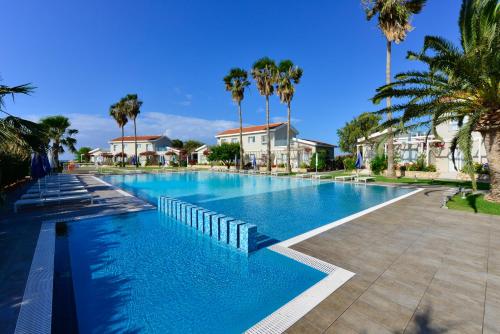 a large swimming pool with palm trees and houses at Mon Repos Hotel in Ayia Napa