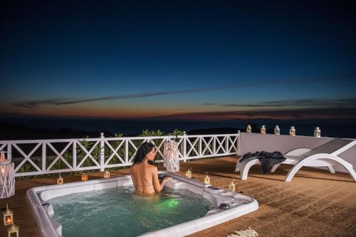 a man sitting in a bath tub on a balcony at Oia Sunset Villas in Oia