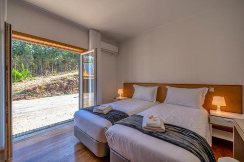 a bedroom with two beds and a large window at Central Suítes Arouca in Arouca