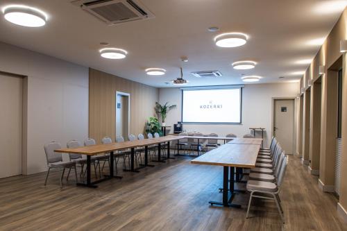 a conference room with tables and chairs and a projection screen at Hotel Kozerki in Kozerki