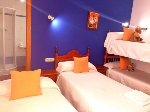 a room with three beds and a blue wall at Hostal Restaurante Ego's in Campo de Criptana
