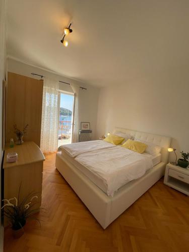 a bedroom with a large white bed and a window at Apartment Sea in Supetarska Draga