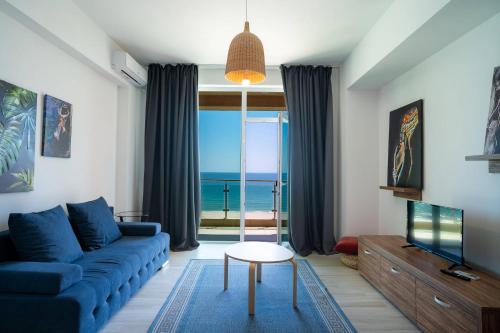 a living room with a blue couch and a view of the ocean at Rezident Eforie Nord in Eforie Nord