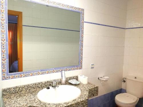 a bathroom with a sink and a toilet and a mirror at Hostal Restaurante Ego's in Campo de Criptana