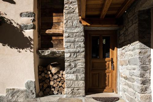a building with a door and a pile of logs at La Gruba Relais in Gaby