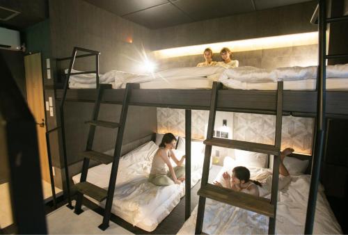 a group of people sitting on top of bunk beds at trive sakae 最大7名宿泊可能 矢場町駅徒歩3分 栄 大須観音スグ in Nagoya