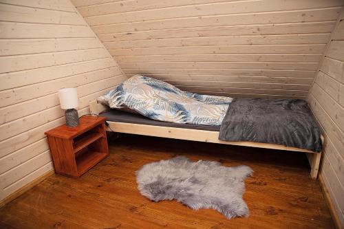 Kleines Zimmer mit einem Bett und einem Teppich in der Unterkunft Nowe Domki w Borsku z Balią kąpielową in Borsk