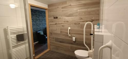 a bathroom with a toilet and a wooden wall at Hotel Lemmenhof in Ell