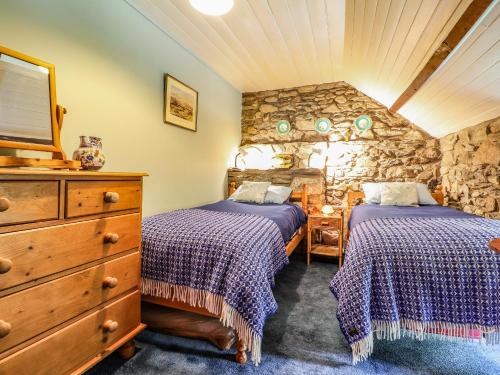 a bedroom with two beds and a stone wall at Tyddyn Bach in Newport Pembrokeshire