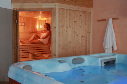 une femme assise dans une baignoire dans une pièce dans l'établissement Hôtel Le Vétiné, à Le Valtin