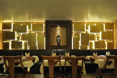 a restaurant with tables and a picture of a vase on the wall at Hotel The Sojourn in Kolkata