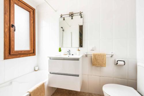 a bathroom with a sink and a toilet and a mirror at Villa Tramontana in Cala en Blanes