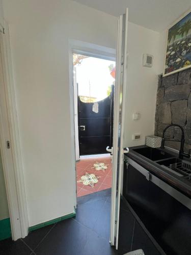 a kitchen with a door open to a kitchen with a sink at Smeraldino in Ischia
