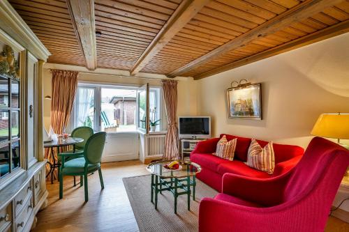 a living room with a red couch and chairs at Hotel und Restaurant Jörg Müller in Westerland (Sylt)