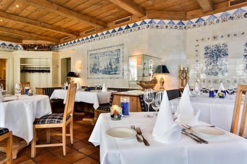 a dining room with white tables and chairs at Hotel und Restaurant Jörg Müller in Westerland (Sylt)