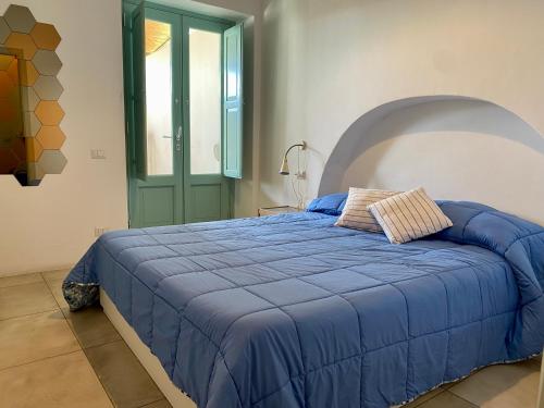 ein Bett mit blauer Decke in einem Schlafzimmer in der Unterkunft Appartamenti Alba&Tramonto in Stromboli