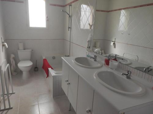 a bathroom with two sinks and a toilet at Chez Didier et Myriam in Portiragnes