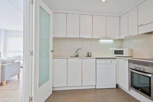 a kitchen with white cabinets and a sink at Apartaments Pepita Bandert in Cambrils