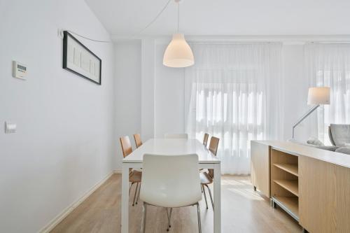 a white dining room with a white table and chairs at Apartaments Pepita Bandert in Cambrils