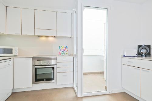 a white kitchen with white cabinets and a mirror at Apartaments Pepita Bandert in Cambrils