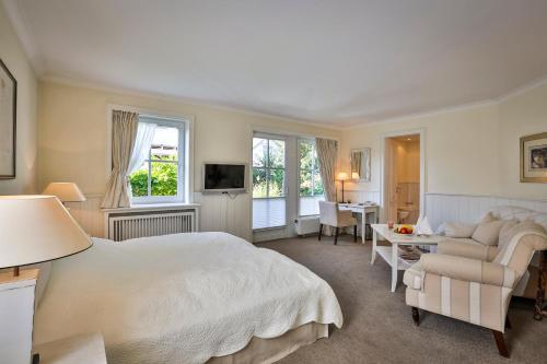 a bedroom with a bed and a couch and a table at Hotel und Restaurant Jörg Müller in Westerland (Sylt)