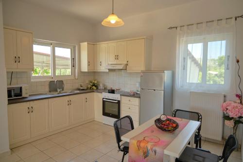 a kitchen with white cabinets and a table with a bowl of fruit on it at Morfis Getaway Apartment in Zakynthos