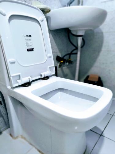 a white toilet with the lid up in a bathroom at Entire Studio Apt/Suite near Mall/Metro/ExpoMart in Noida