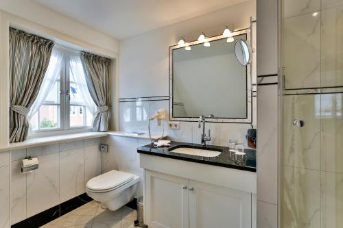 a bathroom with a toilet and a sink and a mirror at Hotel und Restaurant Jörg Müller in Westerland (Sylt)