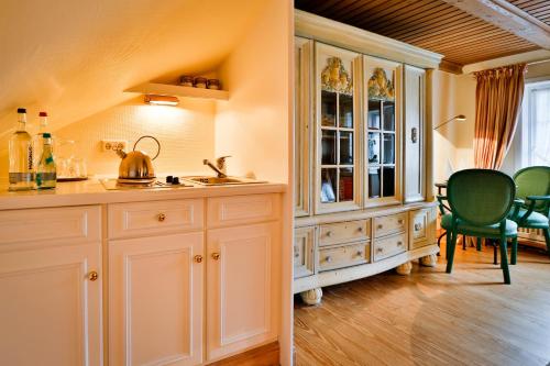 a kitchen with white cabinets and a table and chairs at Hotel und Restaurant Jörg Müller in Westerland (Sylt)