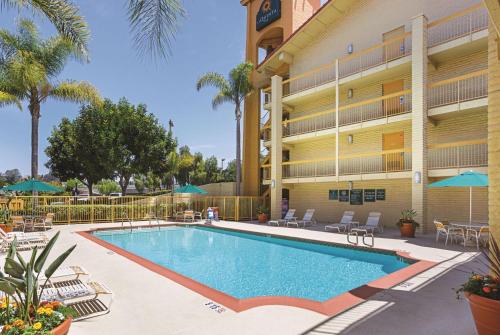 une piscine avec des palmiers en face d'un hôtel dans l'établissement La Quinta Inn by Wyndham San Diego Chula Vista, à Chula Vista