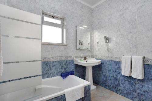 a bathroom with a white tub and a sink at Cantinho da Sara in Portimão