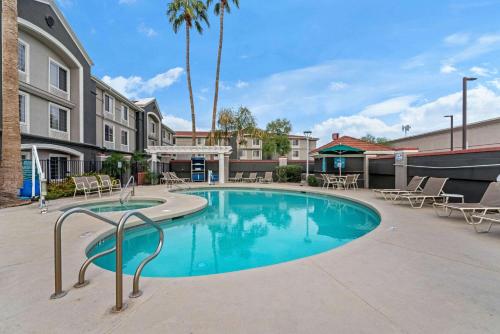 una piscina en un patio con sillas y un edificio en La Quinta by Wyndham Phoenix Scottsdale en Scottsdale