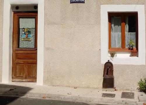 budynek z drzwiami i skrzynką pocztową przed nim w obiekcie Charmant Studio dans l’Ancienne Mairie w mieście Saint-Laurent-le-Minier
