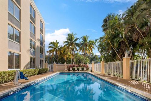 a swimming pool in front of a building with palm trees at La Quinta by Wyndham Sunrise in Sunrise