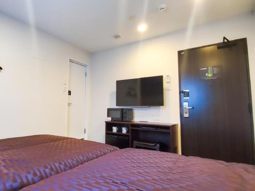 a hotel room with a bed and a desk with a tv at HOTEL LiVEMAX Yokohama Stadium Mae in Yokohama