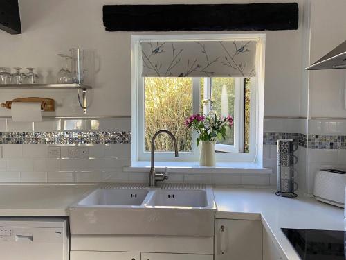 a white kitchen with a sink and a window at Swift Cottage in Liskeard