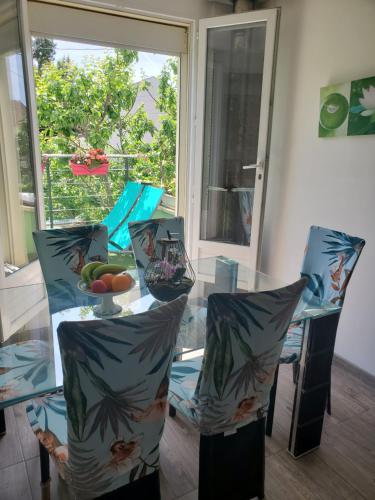 a glass table and chairs with a bowl of fruit on it at Logement calme et ensoleillé dans maison de ville in Villejuif