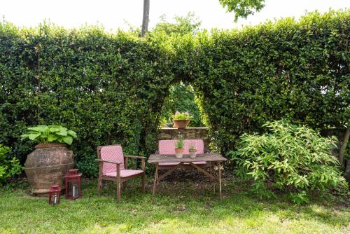 a garden with a table and chairs and a hedge at Villa Poggio Cherici by Mmega in Rignano sullʼArno