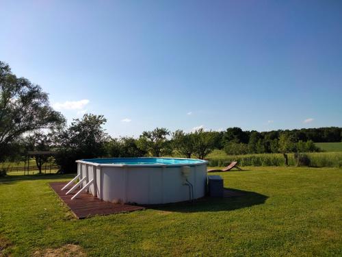 - un grand bain à remous dans une cour avec un champ dans l'établissement La Grange à outeaux, à Montpont-en-Bresse