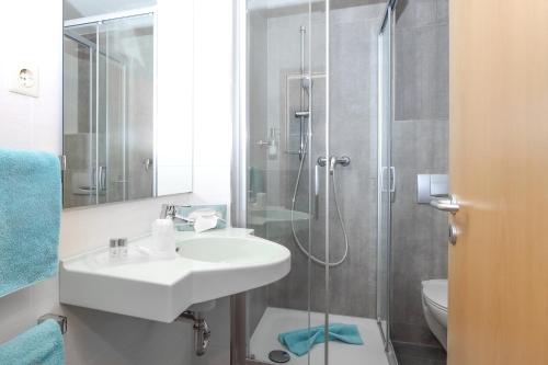 a white bathroom with a sink and a shower at Parkhotel Flora in Bad Grund